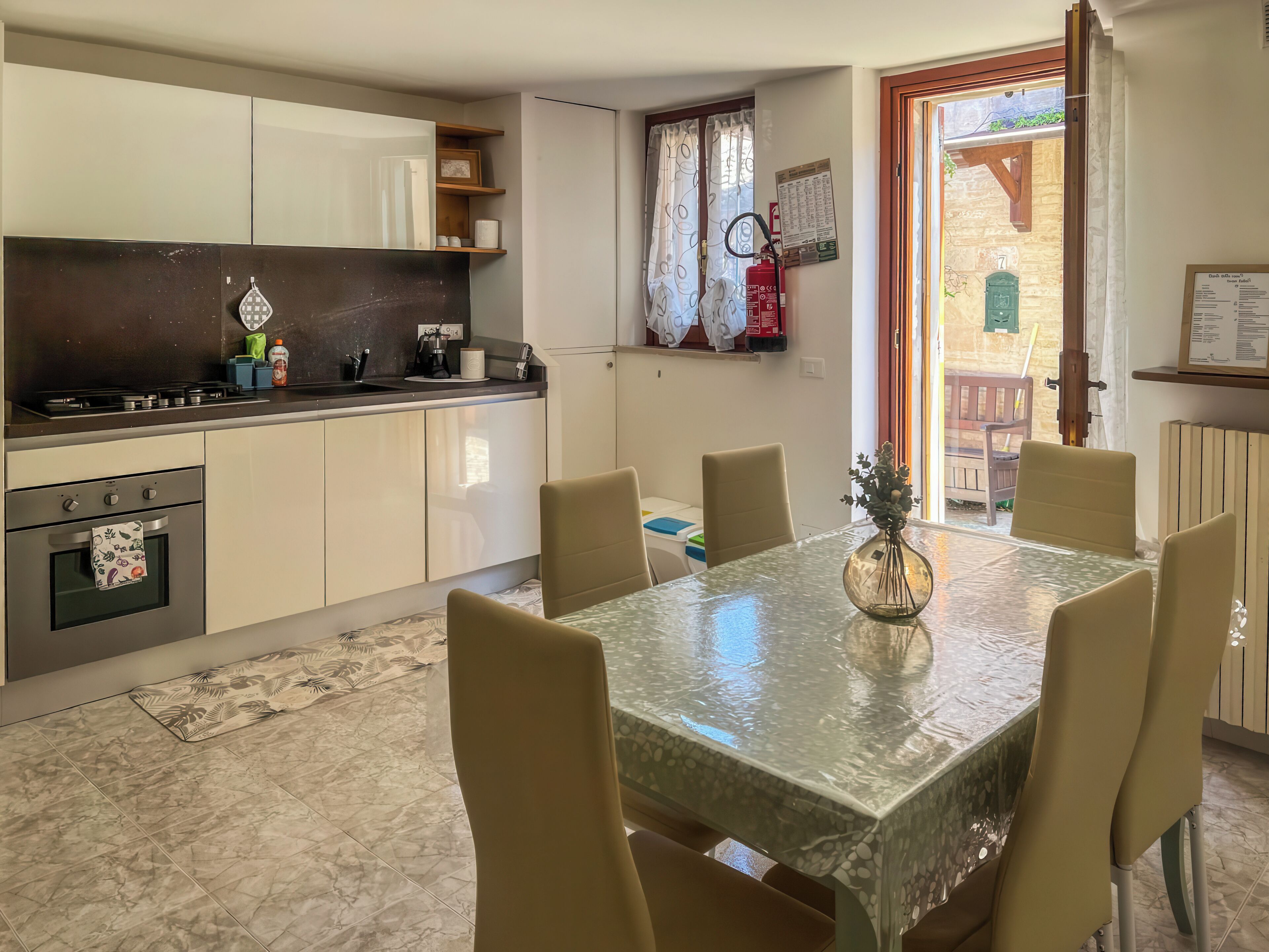 Een moderne keuken met een eethoek, inclusief een tafel met stoelen, een fornuis en een brandblusser.