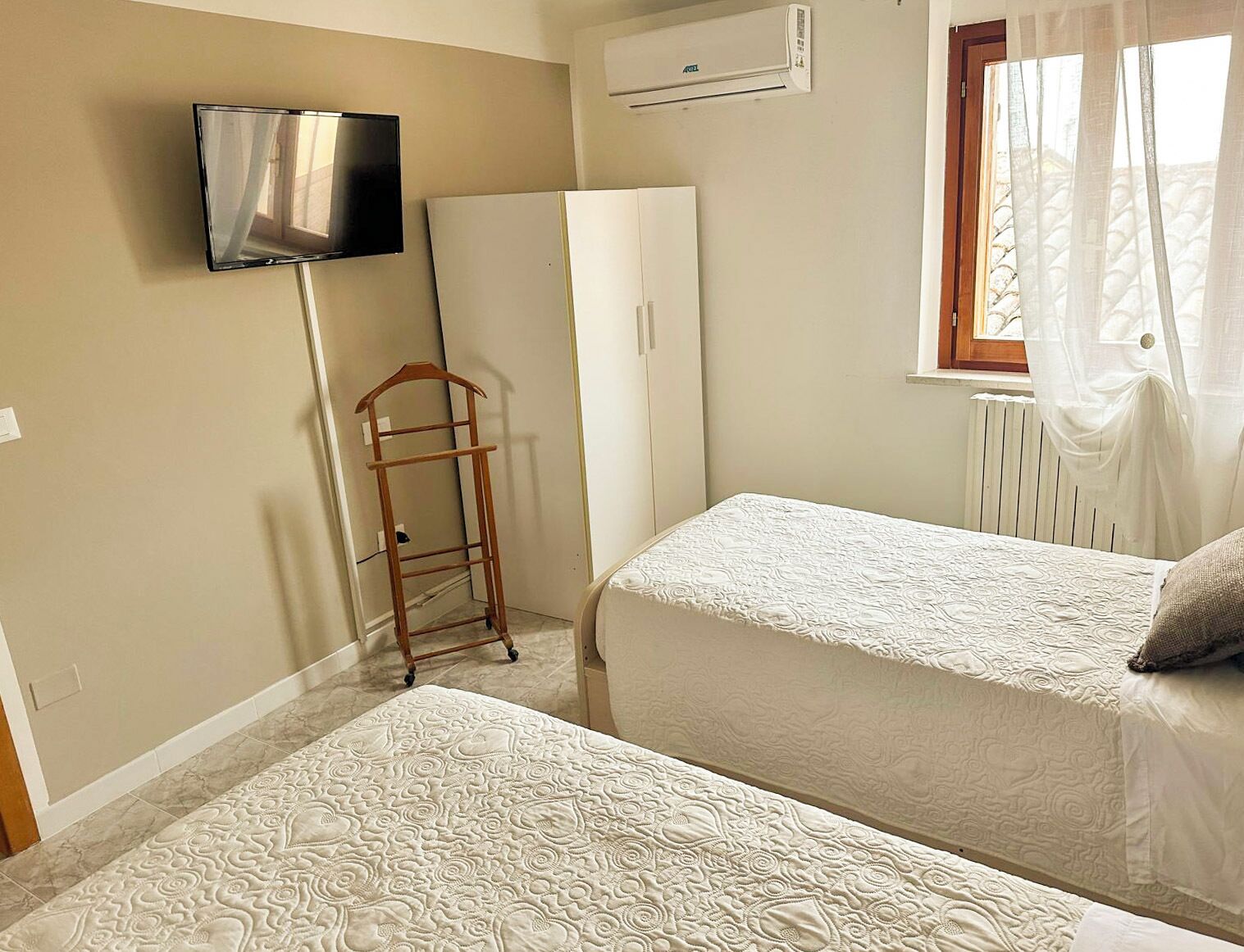 Ein Schlafzimmer mit zwei Betten, einem Kleiderschrank, einem Fernseher und einer Heizung.