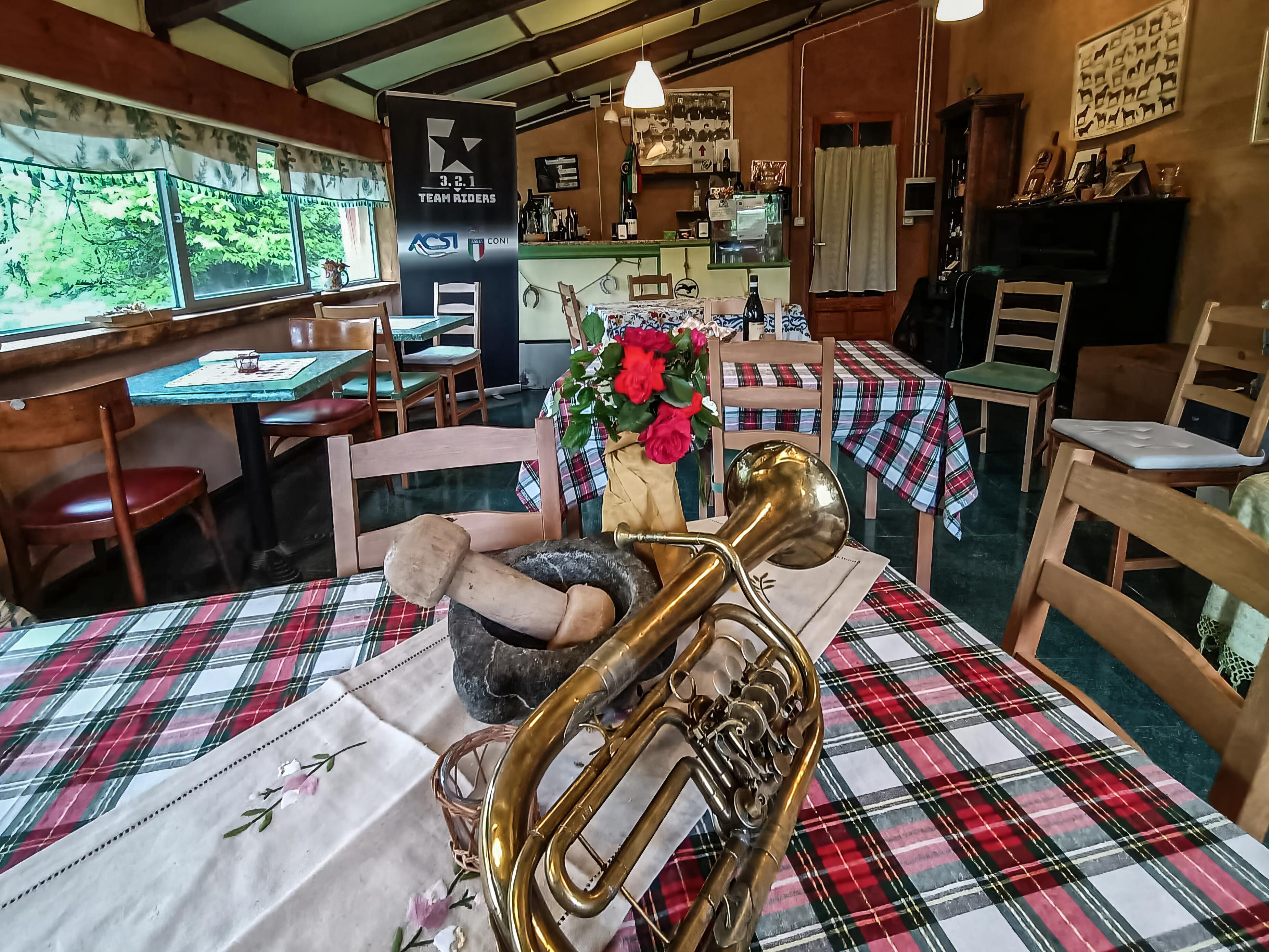 A restaurant with wooden furniture, a brass trombone on the table, and a banner for Team Riders.