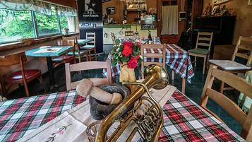 A restaurant with wooden furniture, a brass trombone on the table, and a banner for Team Riders.
