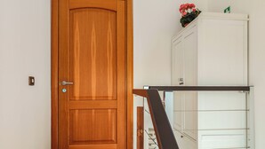Eine Holztür, ein weißes Schranksystem mit Pflanze und eine Treppe mit Geländer.