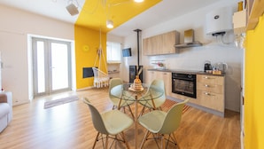 A modern kitchen with wooden cabinets, a dining table with chairs, and a large window. - Casa Argo Guest House (Bisaccia)