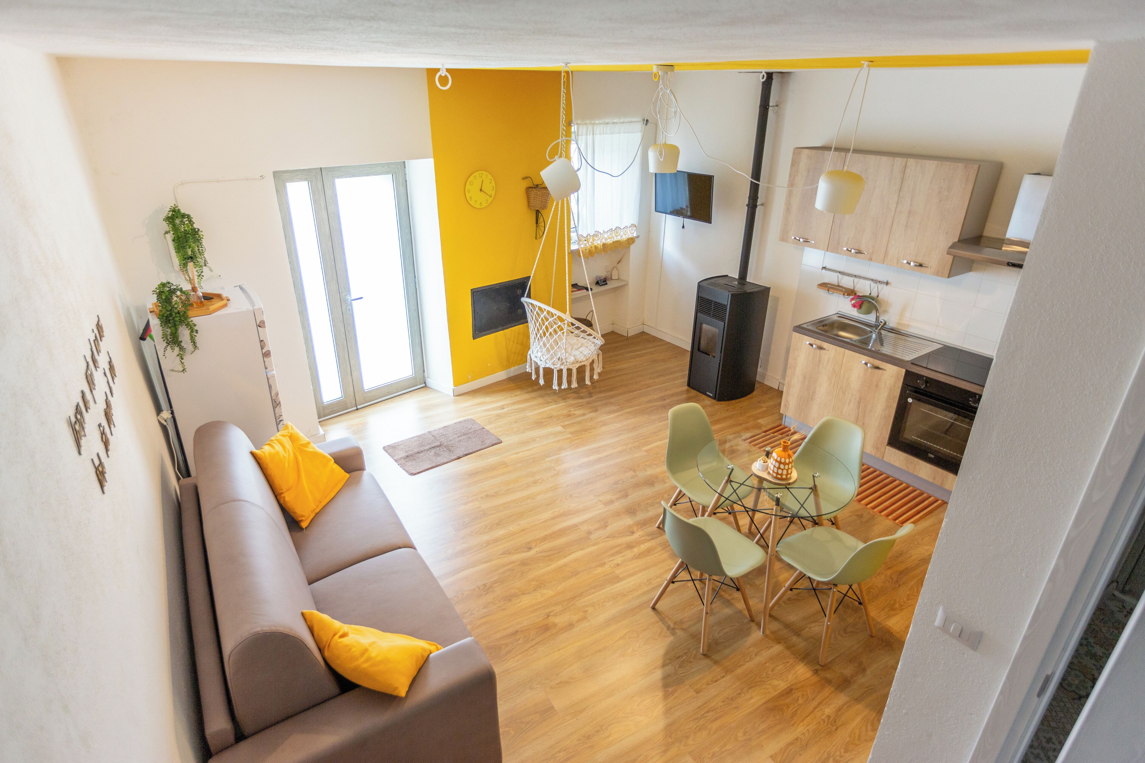Un espacio habitable moderno con sofá, mesa de comedor, sillas y una zona de cocina.