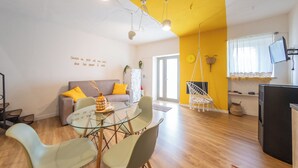 A modern living room with a glass dining table, a sofa with yellow cushions, and a hanging chair. - Casa Argo Guest House (Bisaccia)