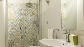 Un baño con ducha, inodoro, lavamanos y espejo.