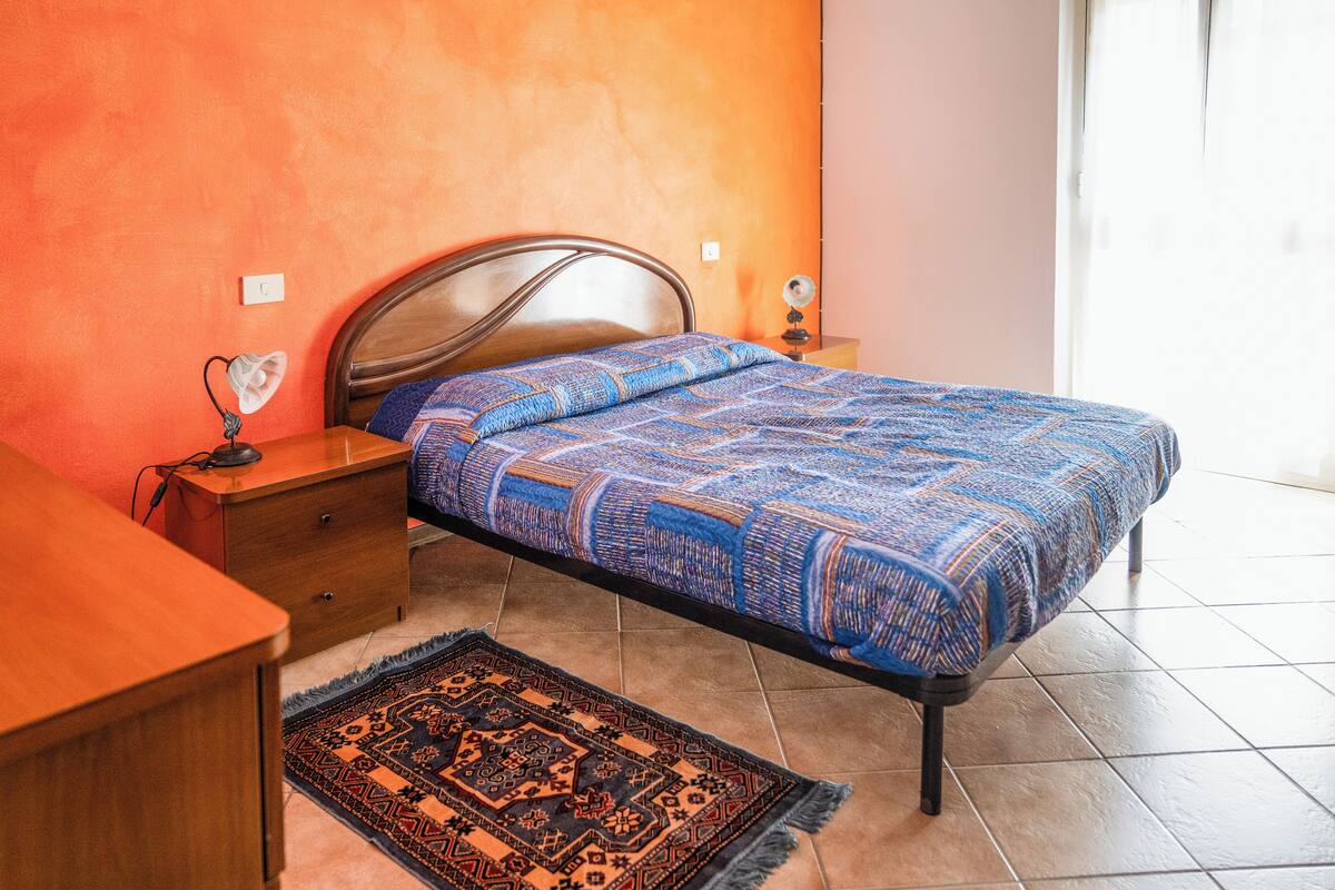 A bedroom with a bed, nightstand, and a small table.