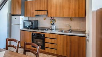 Cocina compacta con armarios de madera, microondas, cafetera y lavabo.