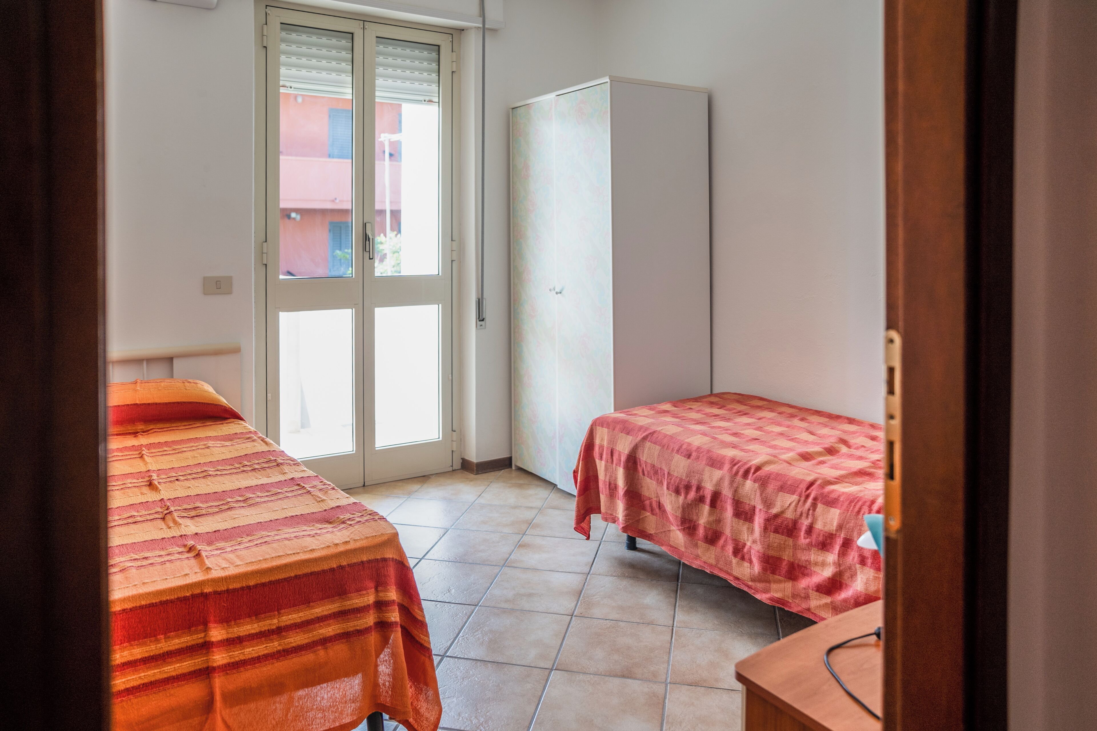 Ein Zimmer mit zwei Betten, einem Kleiderschrank und einem Fenster mit Jalousien.
