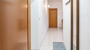 A hallway with a wooden door, a light fixture, and a small rug. - Casa Frida (Roccagloriosa)