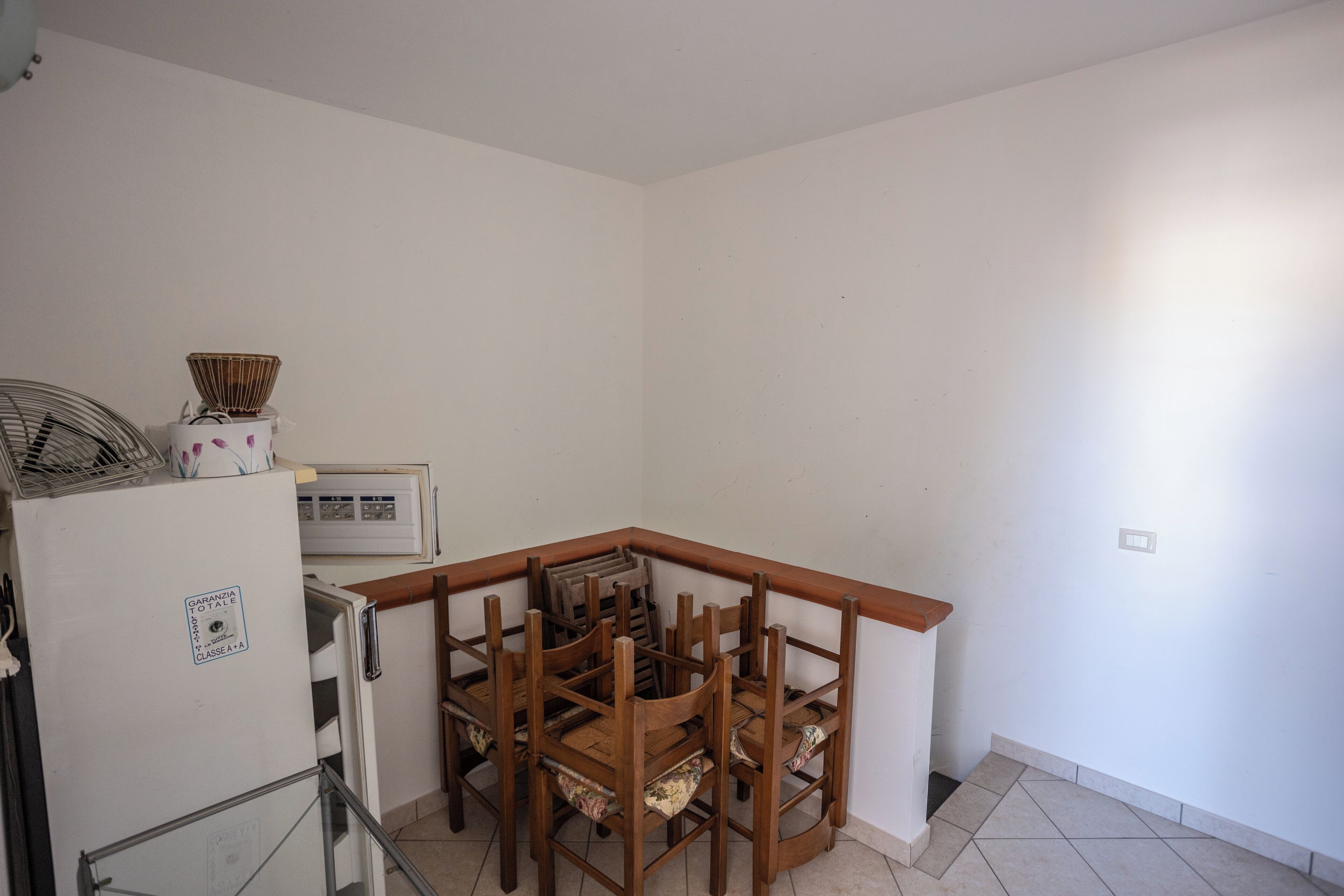 Una pequeña cocina con refrigerador, microondas y una mesa de comedor con sillas.