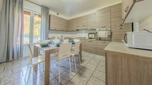 A modern kitchen with wooden cabinets, a dining table with chairs, and a microwave. - Villa Maddalena (Scala)
