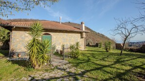 A stone house with a tiled roof, a green door, and a stone pathway leading to it. - Villa Maddalena (Scala)