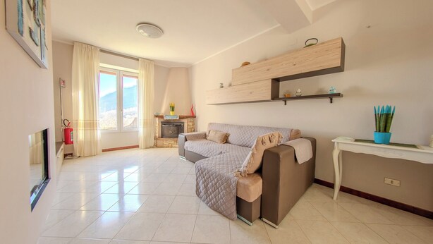 A modern living room with a sectional sofa, a fireplace, and a dining area with a table and chairs. - Villa Maddalena (Scala)