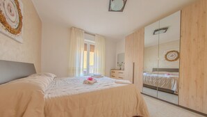 A bedroom with a bed, a wardrobe, a mirror, and a window with curtains. - Villa Maddalena (Scala)