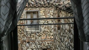 A view through a window with a stone wall and a tiled roof. - Brother'S Home (Civitella Casanova)