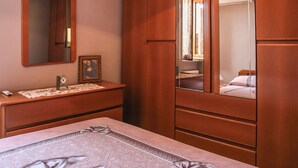 A bedroom with a wooden dresser, a bedside table, a mirror, and a bed with a patterned bedspread. - Brother'S Home (Civitella Casanova)