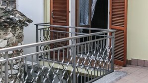 A balcony with a metal railing, a stone wall, and a wooden door with shutters. - Brother'S Home (Civitella Casanova)