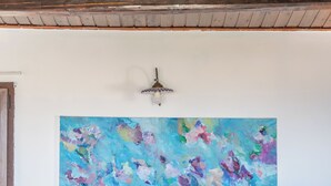 Ein Zimmer mit einem großen abstrakten Gemälde an der Wand, einem Deckenventilator und einer Holztür.