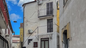 Una calle empedrada y estrecha bordeada por edificios con balcones y una puerta visible.