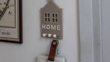 Un élément de décoration à fixer au mur, en forme de maison, sur lequel est inscrit le mot « HOME ».