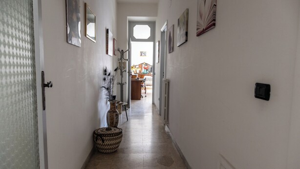 A narrow hallway with a tiled floor, a large woven basket, and a door leading to a room. - Il Ritrovo Degli Artisti (Castrovillari)