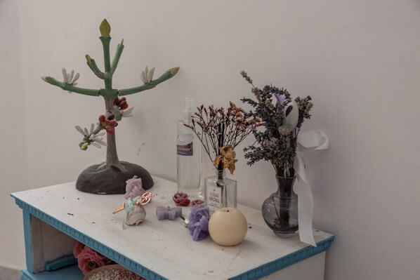 Una pequeña mesa con borde azul que sostiene varios objetos decorativos, como un pequeño árbol, jarrones con flores secas y una botella de perfume.