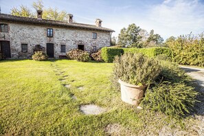 Un bâtiment en pierre avec un jardin devant.