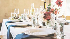 A dining table set with plates, cutlery, and glasses, with a menu stand and floral centerpiece. - Antica Cantina Emilia (Reggio Calabria)