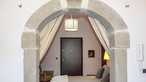 A bedroom with a stone archway, a bed with pillows, a bedside lamp, and a door. - Antica Cantina Emilia (Reggio Calabria)