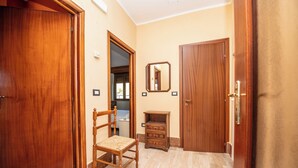 A hallway with wooden doors, a chair, a small wooden cabinet, and a mirror on the wall. - La Vecchia Cascina (Atena Lucana)