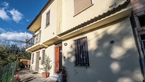 A two-story building with a balcony, a wooden door, and a window with bars. - La Vecchia Cascina (Atena Lucana)
