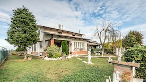 Una casa con un césped cuidado, un árbol grande y una estatua en el jardín delantero.