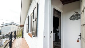 Un edificio blanco con un letrero que dice 'Welcome', un acceso con azulejos y una puerta de madera.