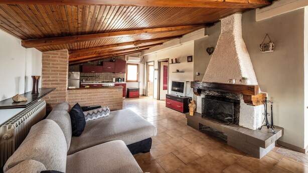 Un salón espacioso con chimenea, una cocina al fondo y una zona de estar acogedora.