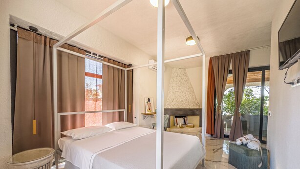 A hotel room with a four-poster bed, a fireplace, a small seating area, and a view of the outdoors.