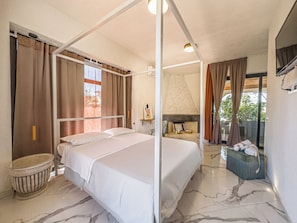 A hotel room with a four-poster bed, a fireplace, a small seating area, and a view of the outdoors. - Villa Oidor - Cilento (Ascea)