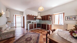 Un grand espace de vie comprenant un canapé, une table à manger et une cuisine dotée de meubles en bois et d’un plan de travail carrelé.