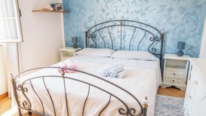 A neatly made bed with a metal frame, a bedside table with a lamp, and a wall with a blue pattern. - Casa A Modolo - Francesca (Modolo)