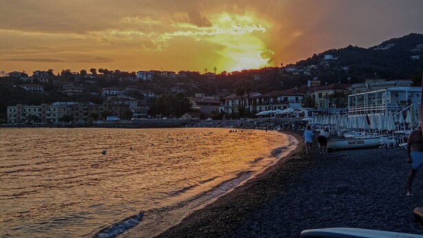 A beach with a sunset, a row of beach umbrellas, and a boat named SALVIAZAGGIO. - La Giulietta (Tortorella)