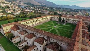 A historical building with a courtyard, surrounded by residential buildings and mountains in the background. - La Giulietta (Tortorella)