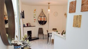 A modern interior with a marble floor, a round mirror, a console table with decorative items, a dining area with chairs, and a wall-mounted clock. - La Giulietta (Tortorella)