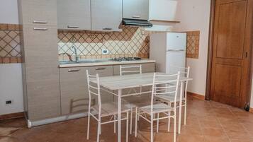 Cocina compacta con mesa y sillas, estufa a gas y refrigerador.