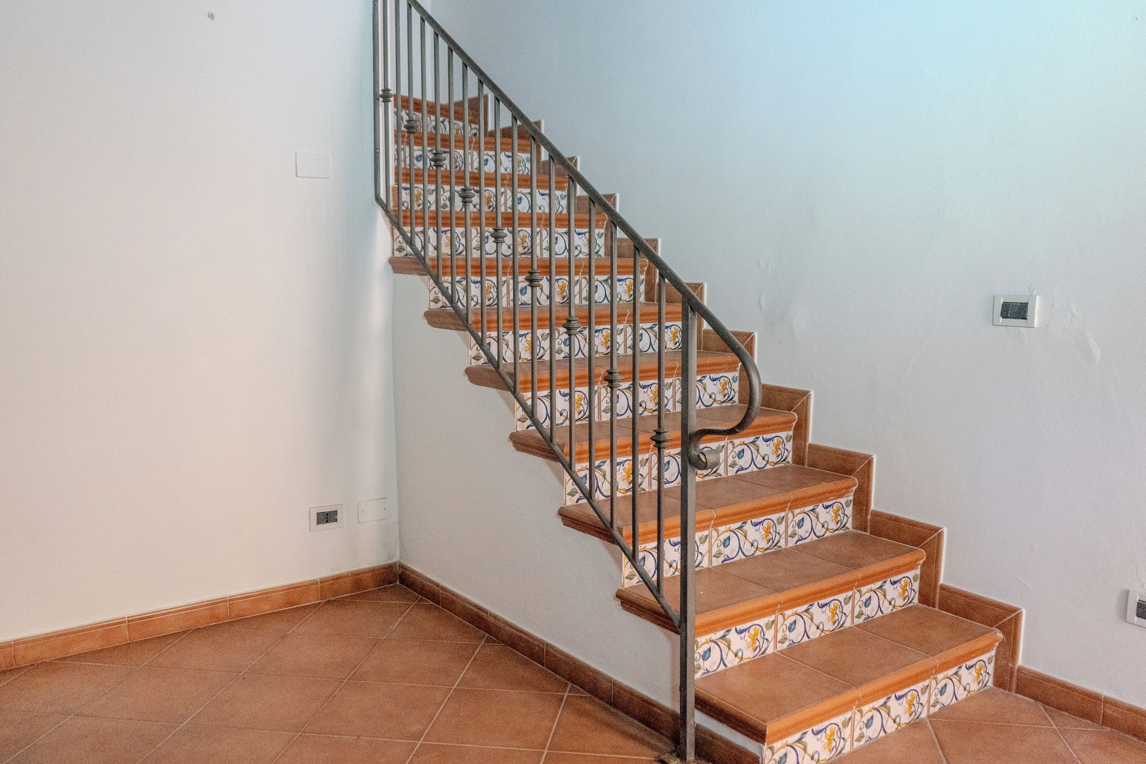 A staircase with a metal railing and patterned steps, leading to an upper floor.