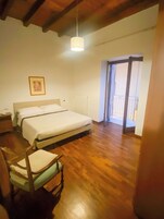 Un dormitorio con una cama grande, una silla de madera, un radiador y un balcón.
