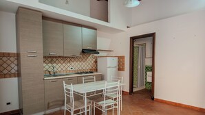 A kitchen with a dining table and chairs, a refrigerator, and cabinets. - La Discesa Di San Giuseppe (Termini Imerese)