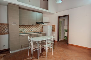 A kitchen with a dining table and chairs, a refrigerator, and cabinets.