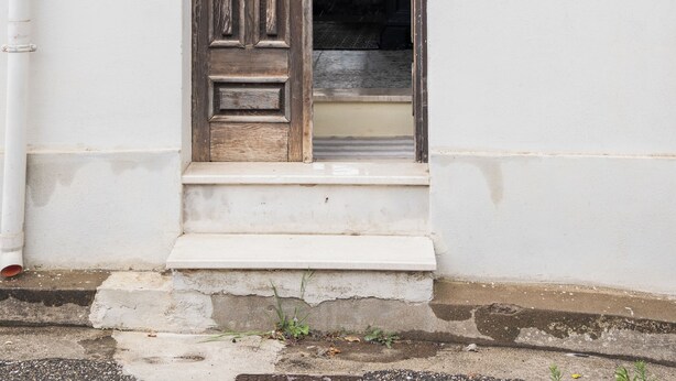 A white building with a wooden door and a small window.