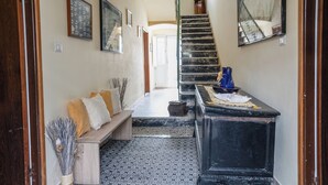A hallway with a wooden bench, a black cabinet, and a patterned rug.