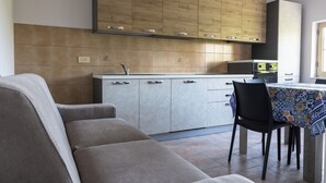 Una cocina moderna con armarios de madera, horno empotrado y un comedor con mesa y sillas.