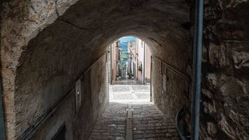 A stone archway leading to a cobblestone street with buildings in the background.
